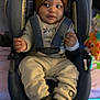 baby, child, car_seat, beanie, clothing, toy, giraffe, indoor, smiling, face, person, cute, comfort, seatbelt, infant, warm, socks, apparel, young, portrait