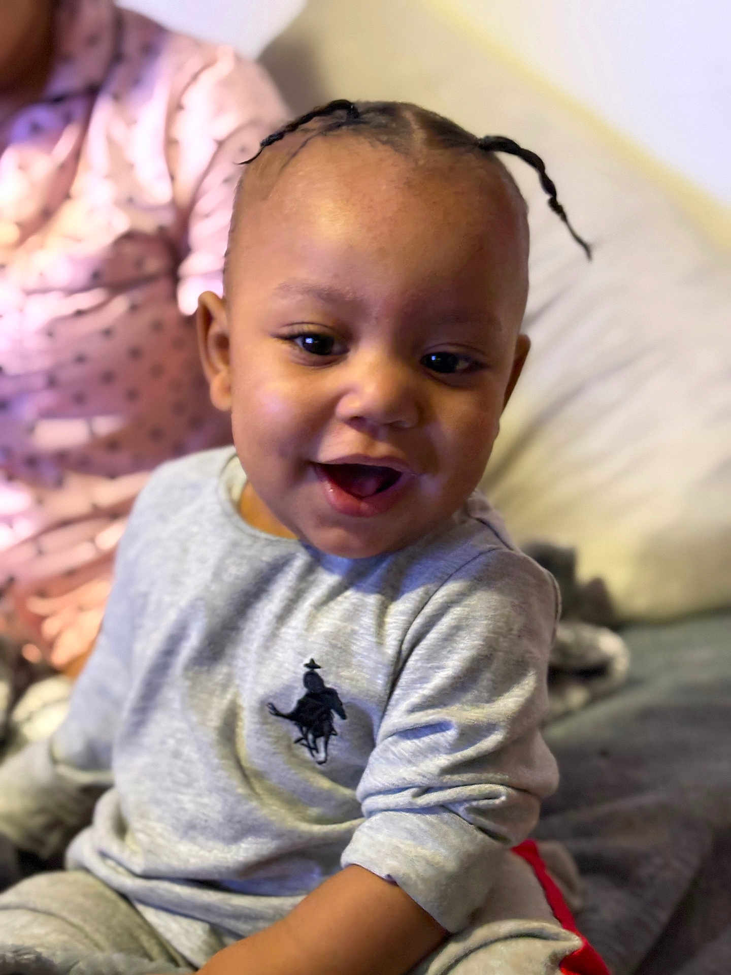 Nyairr is registered to the contest to win money with this photo: toddler, child, smiling, braided_hair, gray_sweatshirt, indoor, bed, pillow, blanket, happy, person, cute, young_child, seated, casual_clothing, portrait, cozy, relaxed, home, joyful