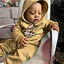 Nyairr joined the competition — help win amazing prizes! toddler, child, hoodie, beige_clothing, sitting, chair, indoor, face, curious, furniture, cozy, casual_clothing, young_child, baby, person, home, blurred_background, soft_lighting, hand, expression