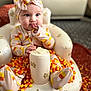 baby, infant, child, pajamas, headband, candy_corn, toy_chair, teddy_bear_pattern, indoor, carpet, cute, sitting, curious, hand_in_mouth, colorful, soft_toys, plush, comfort, portrait, bright