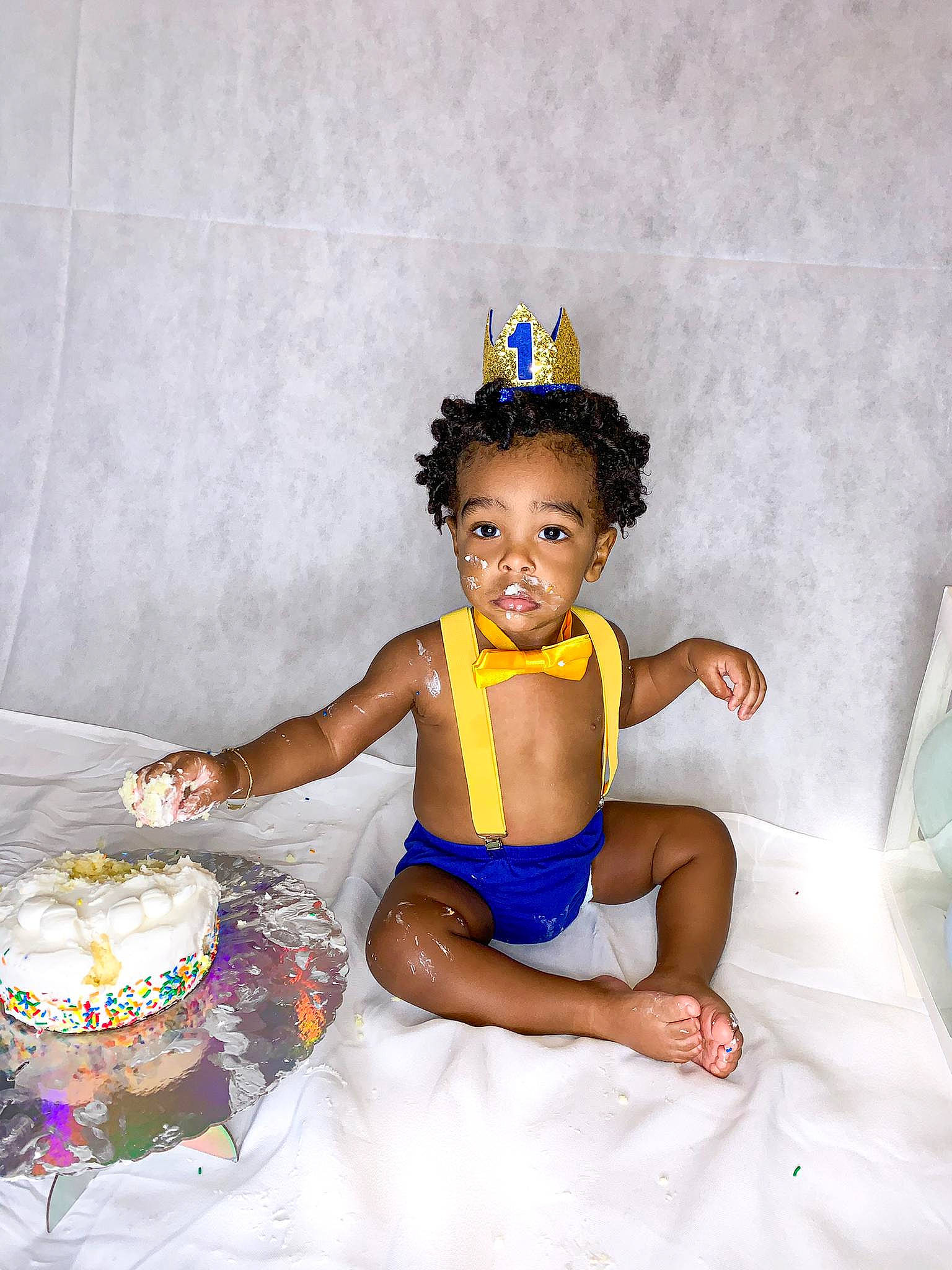 Jayvion is registered to the contest to win money with this photo: abdomen, baby_toddler_clothing, bathing, birthday_cake, cake, cake_decorating, child, dessert, dress, event, food, fun, happy, icing, leg, party_supply, person, sitting, sugar_cake, thigh