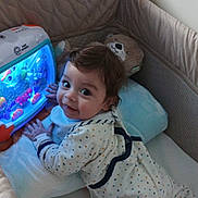 Jude participe au concours pour gagner de l'argent avec cette photo : baby, crib, toy, pillow, teddy_bear, onesie, infant, child, indoor, playtime, cute, smiling, face, person, soft_toy, colorful, happy, baby_einstein, fabric, sleeping_area