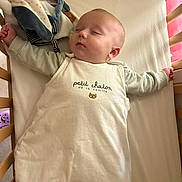 Maxence participe au concours pour gagner de l'argent avec cette photo : baby, sleeping, crib, sleeping_bag, infant, cute, peaceful, child, indoors, soft_light, face, arm, toy, blanket, wooden_crib, toddler, clothing, head, resting, calm