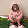 Jade a rejoint le concours — aidez-le/la à gagner de superbes lots ! child, smiling, pink_jacket, hood, slippers, sitting, green_turf, potted_flowers, happy, outdoor, cute, playful, toddler, wall, texture, clothing, footwear, person, garden, casual