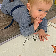 Louis participe au concours pour gagner de l'argent avec cette photo : toddler, child, blonde_hair, gray_clothing, floor, play_mat, indoor, curious, sitting, hand, face, person, home, wooden_floor, toy, paw_print, star, pattern, baby, casual