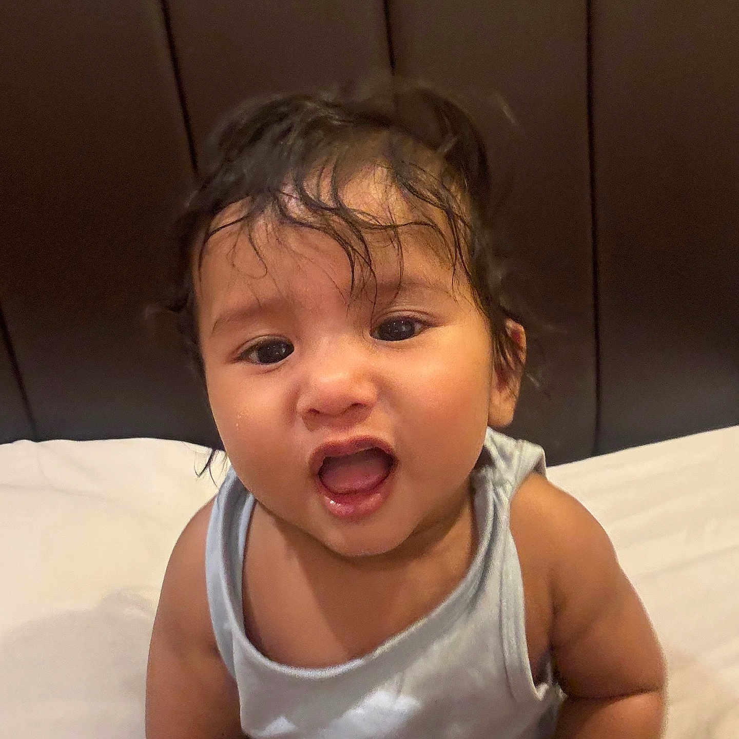 Raayan joined the competition — help win amazing prizes! baby, bed, child, clothing, cute, expression, face, hair, happy, headboard, indoors, infant, mouth, person, pillow, portrait, sitting, skin, tank_top, young