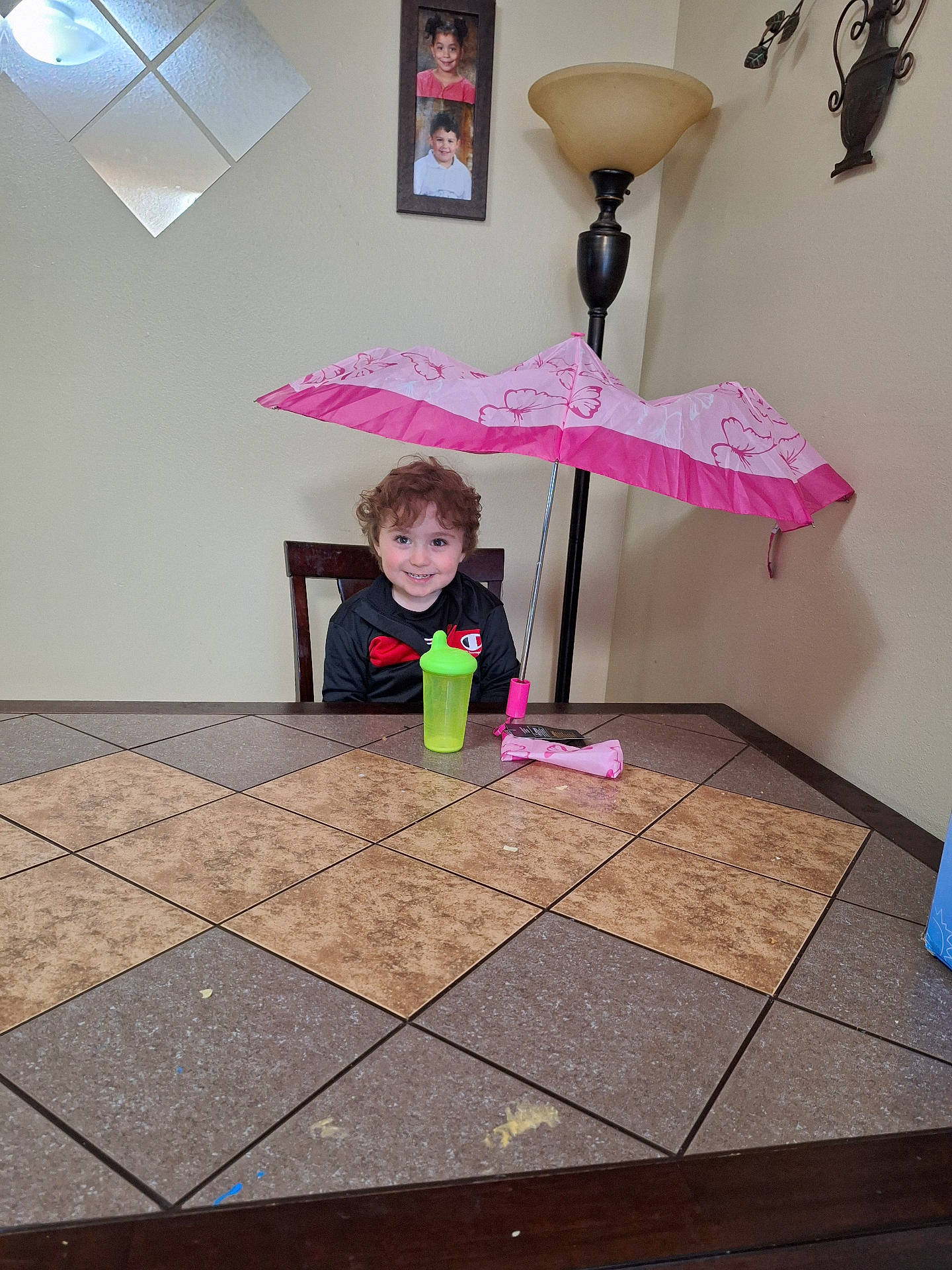 Kingstyn joined the competition — help win amazing prizes! chair, child, curly_hair, drinkware, furniture, green, happy, indoor, lamp, photo_frame, pink, portrait, sippy_cup, smiling, table, tile, umbrella, wall, wooden_chair, young_child