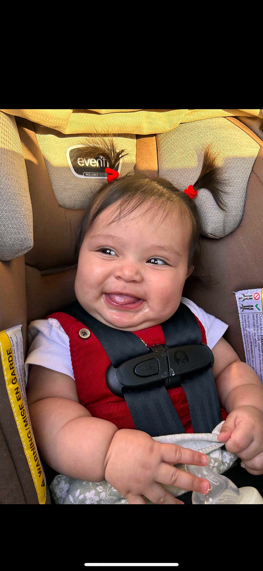 Amelia joined the competition — help win amazing prizes! baby, child, car_seat, pigtails, red_clothing, smiling, happy, infant, cute, seat_belt, bottle, skin, face, hands, indoors, child_safety, adorable, young, person, portrait