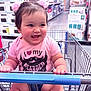 baby, child, shopping_cart, store, aisle, pink, hair_ties, shirt, cute, happy, smile, chubby, clothing, retail, indoor, person, holding, funny_shirt, sitting, shopping