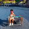 child, toddler, girl, smiling, playground, playground_equipment, spring_rider, outdoor, park, play_area, slide, jungle_gym, sports_surface, sunlight, curly_hair, headband, floral_clothing, sneakers, portrait, happy