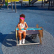Baby Doll is registered to the contest to win money with this photo: child, toddler, girl, smiling, playground, playground_equipment, spring_ride, outdoor, park, play_area, sunlight, trees, rubber_surface, colorful, dress, headband, curly_hair, sneakers, portrait, recreation