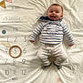 arrow, baby, child, clothing, decorations, face, floor, happy, infant, lying_down, milestone_blanket, months, numbers, pants, portrait, smiling, socks, striped_shirt, tongue_out, wooden_ring