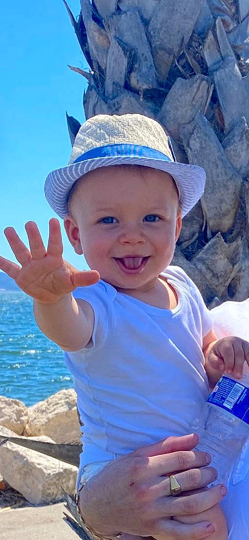 Luciano participe au concours pour gagner de l'argent avec cette photo : azure, baby_toddler_clothing, blue, body_of_water, cap, eye, facial_expression, gesture, hand, happy, hat, headwear, human_body, joy, light, organ, person, photograph, skin, smile