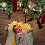 baby, infant, christmas_tree, christmas_lights, red_stocking, floor, pajamas, mat, holiday, smile, indoors, wood_floor, festive, child, decoration, greenery, cozy, cute, lying_down, celebration