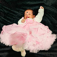 Leïa Thikshitha participe au concours pour gagner de l'argent avec cette photo : adorable, baby, black_blanket, child, cozy, cute, face, footwear, head, indoors, infant, legs, lying_down, one_arm_up, pink_dress, portrait, sleepy, small, soft_texture, white_sweater