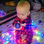Odin is registered to the contest to win money with this photo: baby, child, pajamas, red, black, checkered, christmas_lights, ornament, blue, blanket, holiday, festive, indoors, floor, cute, toddler, sitting, toy, decorations, warm