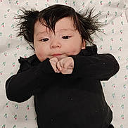 Alexis joined the competition — help win amazing prizes! baby, bed_sheet, black_clothing, child, cute, expression, eyes, face, hair, hands, indoors, infant, lying_down, mouth, patterned_sheet, person, portrait, skin, small_fingers, young_child