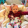 Addison is registered to the contest to win money with this photo: baby, blanket, carpet, casual, child, colorful, cozy, cute, floral_clothing, footwear, furniture, happy, headband, indoor, infant, person, relaxed, sitting, smiling, toy