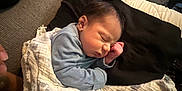 Eli joined the competition — help win amazing prizes! baby, newborn, sleeping, blanket, cushion, pillow, infant, indoor, person, tattoo, hand, furniture, living_room, stroller, basket, floor, carpet, soft_lighting, cozy, rest