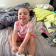 Jo'Mila King joined the competition — help win amazing prizes! bed, blanket, child, comb, curly_hair, cute, hairbrush, happy, indoors, messy_bed, person, pillow, pink_clothing, playful, room, sitting, smiling, toddler, white_shoes, young_child