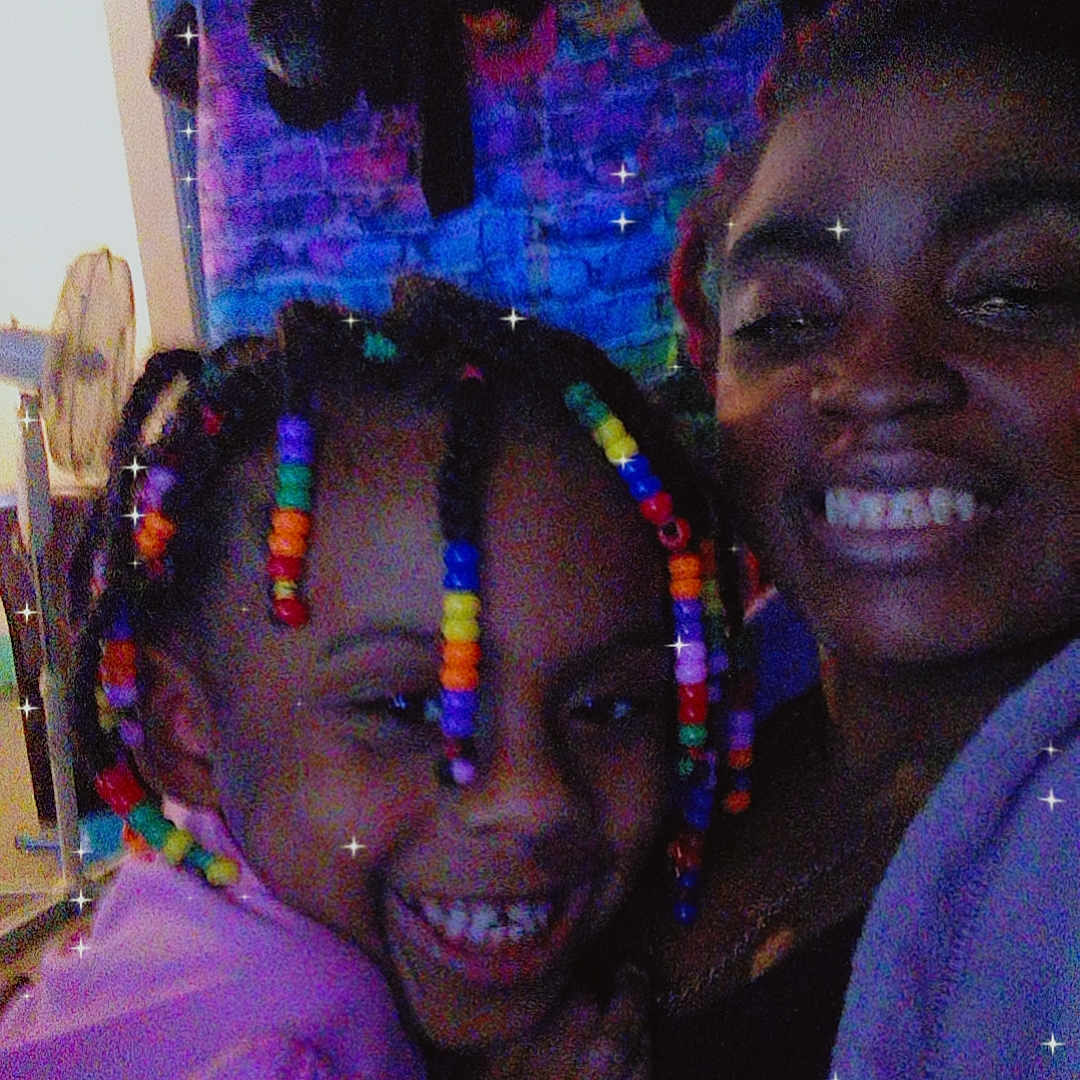 Amora is registered to the contest to win money with this photo: adult, affection, blue_background, casual_clothing, child, closeup, colorful_beads, cozy, family, fun, hair, happy, indoor, joyful, people, portrait, smiling, sparkle_filter, togetherness, warmth