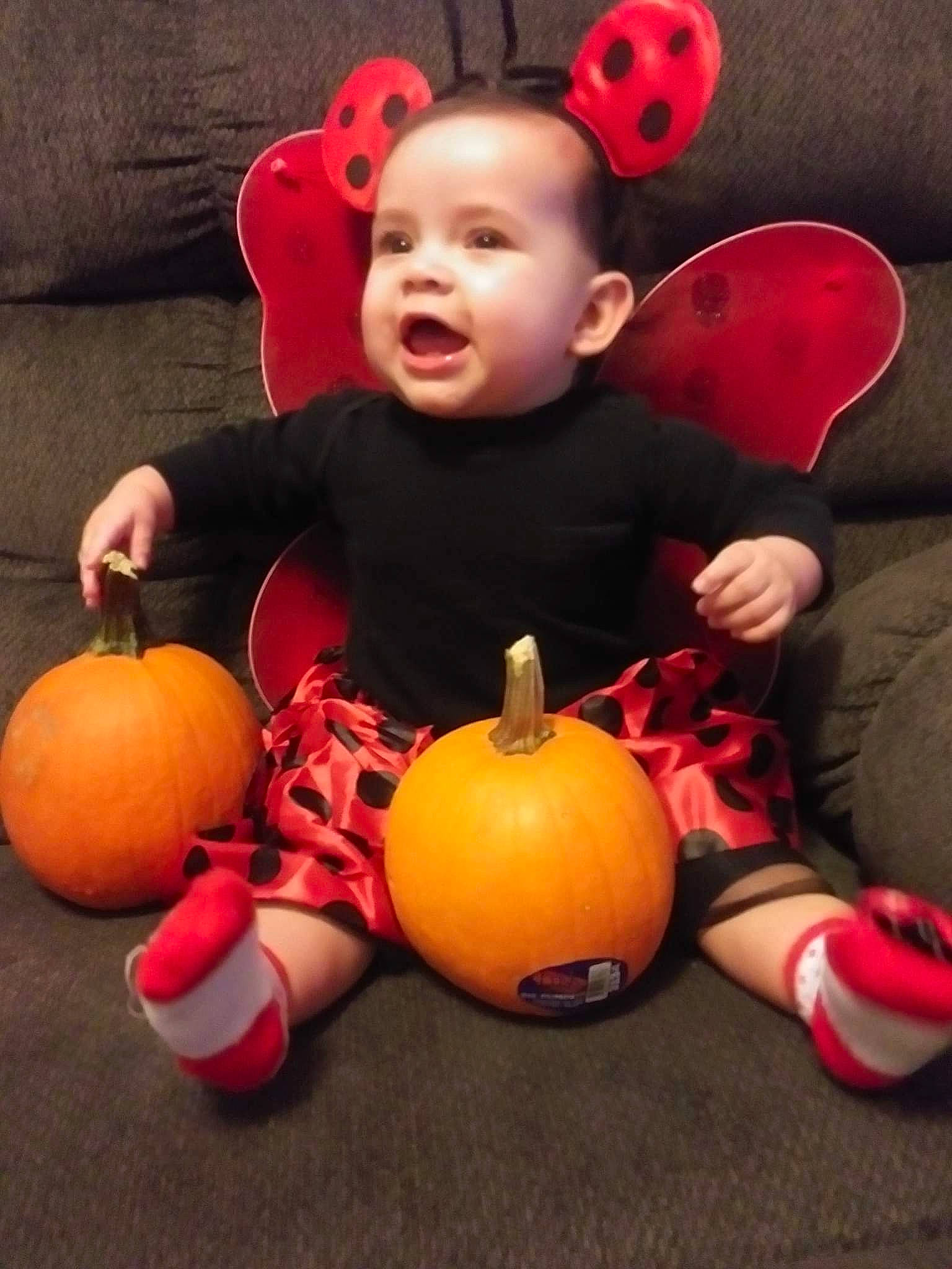 Michaela is registered to the contest to win money with this photo: black, calabaza, eye, face, facial_expression, finger, floor, flooring, happy, head, human_body, leg, orange, organ, person, plant, pumpkin, shoe, toy, winter_squash