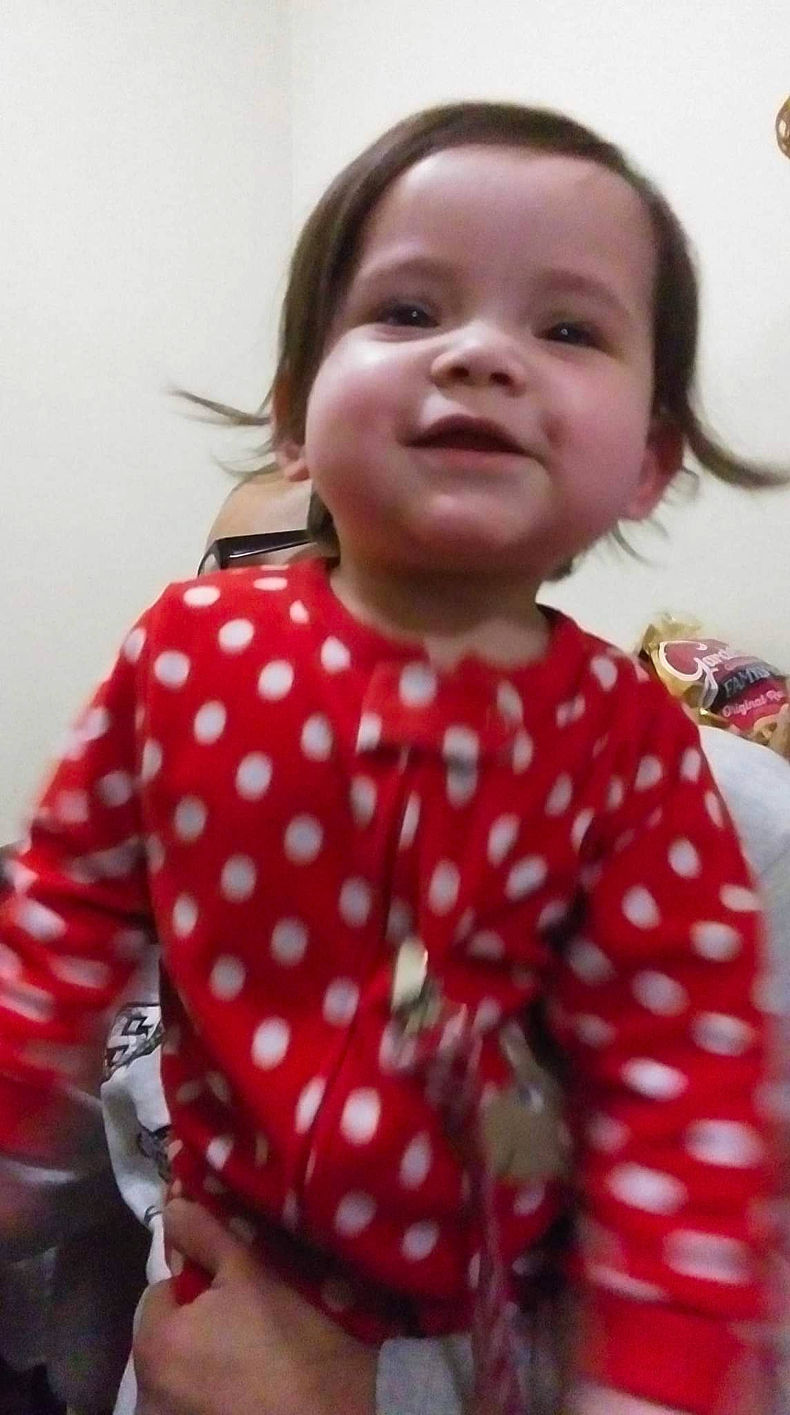 Michaela is registered to the contest to win money with this photo: baby_toddler_clothing, cheek, child, eye, face, facial_expression, gesture, hair, happy, head, joy, lip, neck, nose, pattern, person, pink, plaid, skin, sleeve