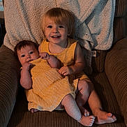 Madelyn joined the competition — help win amazing prizes! child, toddler, baby, yellow_dress, armchair, blanket, smile, happy, sitting, indoor, family, cute, portrait, furniture, cozy, cushion, person, clothing, head, feet