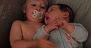 Madelyn is registered to the contest to win money with this photo: toddler, baby, pacifier, onesie, child, cuddling, indoor, pillow, blanket, cute, sleepwear, infant, sibling, young_child, relaxed, soft_light, cozy, bedroom, face, hands