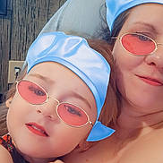 Elizabeth is registered to the contest to win money with this photo: blue_hat, candid, casual, child, closeup, digital_filter, face, family, glasses, hand, headwear, indoor, pink_sunglasses, portrait, skin, smile, together, wall, woman, wood_texture