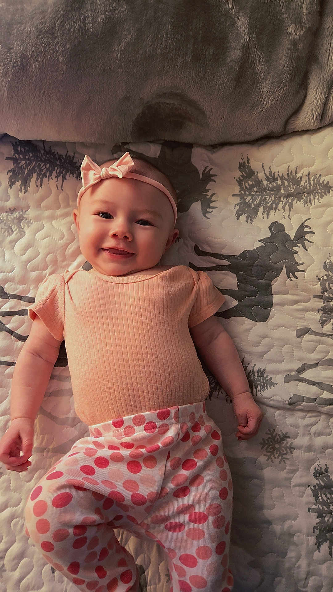 Jalynn is registered to the contest to win money with this photo: baby, smiling, headband, bow, pink, peach_clothing, polka_dot_pants, lying_down, quilted_blanket, reindeer_pattern, snowflake_pattern, infant, cute, portrait, child, indoors, soft_lighting, happy, person, apparel