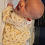baby, smiling, infant, yellow_clothing, floral_pattern, socks, blanket, indoor, happy, cute, lying_down, head, face, skin, person, child, toddler, cozy, warm, soft_texture