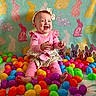 baby, child, smiling, pink_clothing, headband, easter_eggs, colorful, bunny_pattern, blanket, spring, decorations, indoors, happy, cute, festive, sitting, playful, toy, holiday, portrait