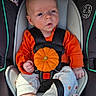 baby, infant, child, car_seat, orange_clothing, pumpkin, autumn, halloween, harness, safety_seat, portrait, sitting, wide_eyed, surprised_expression, facial_expression, hands, bare_feet, pacifier, indoor, close_up