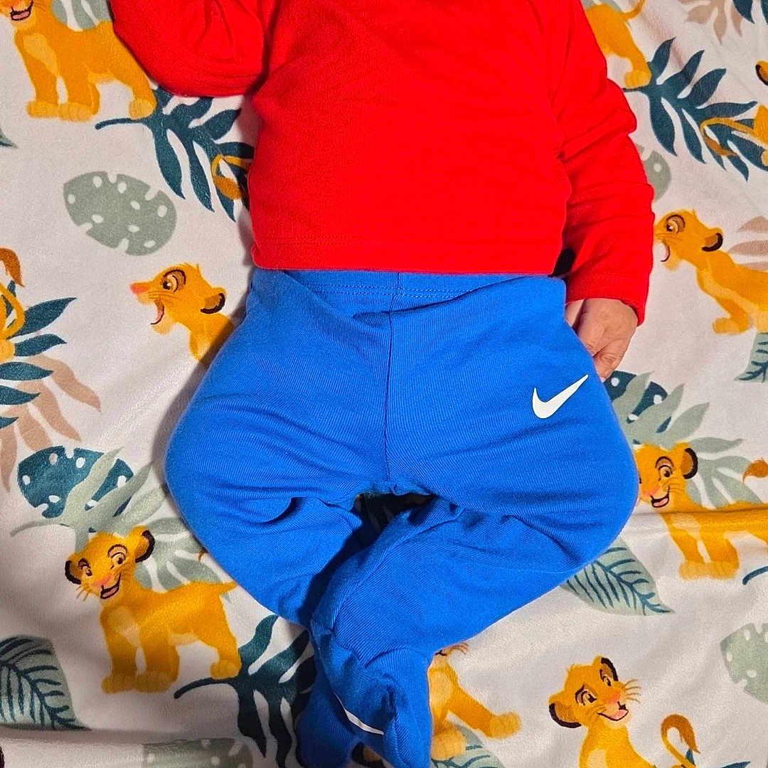 Ky'Mir is registered to the contest to win money with this photo: baby, bedtime, blanket, blue_clothing, cartoon, child, cozy, cute, footed_pants, hat, indoor, infant, lion_king, nike, pacifier, pattern, red_clothing, resting, sleeping, toddler