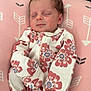 Addilynn is registered to the contest to win money with this photo: baby, newborn, sleeping, onesie, floral_pattern, pink_cushion, arrow_pattern, infant, cute, peaceful, resting, soft_fabric, indoors, child, portrait, cozy, small, closed_eyes, human, relaxing