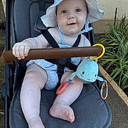 Sloane joined the competition — help win amazing prizes! baby, stroller, hat, plush_toy, baby_clothing, outdoor, child, greenery, pathway, cute, infant, summer, sun_hat, seatbelt, toy, happy, smiling, legs, foot, person