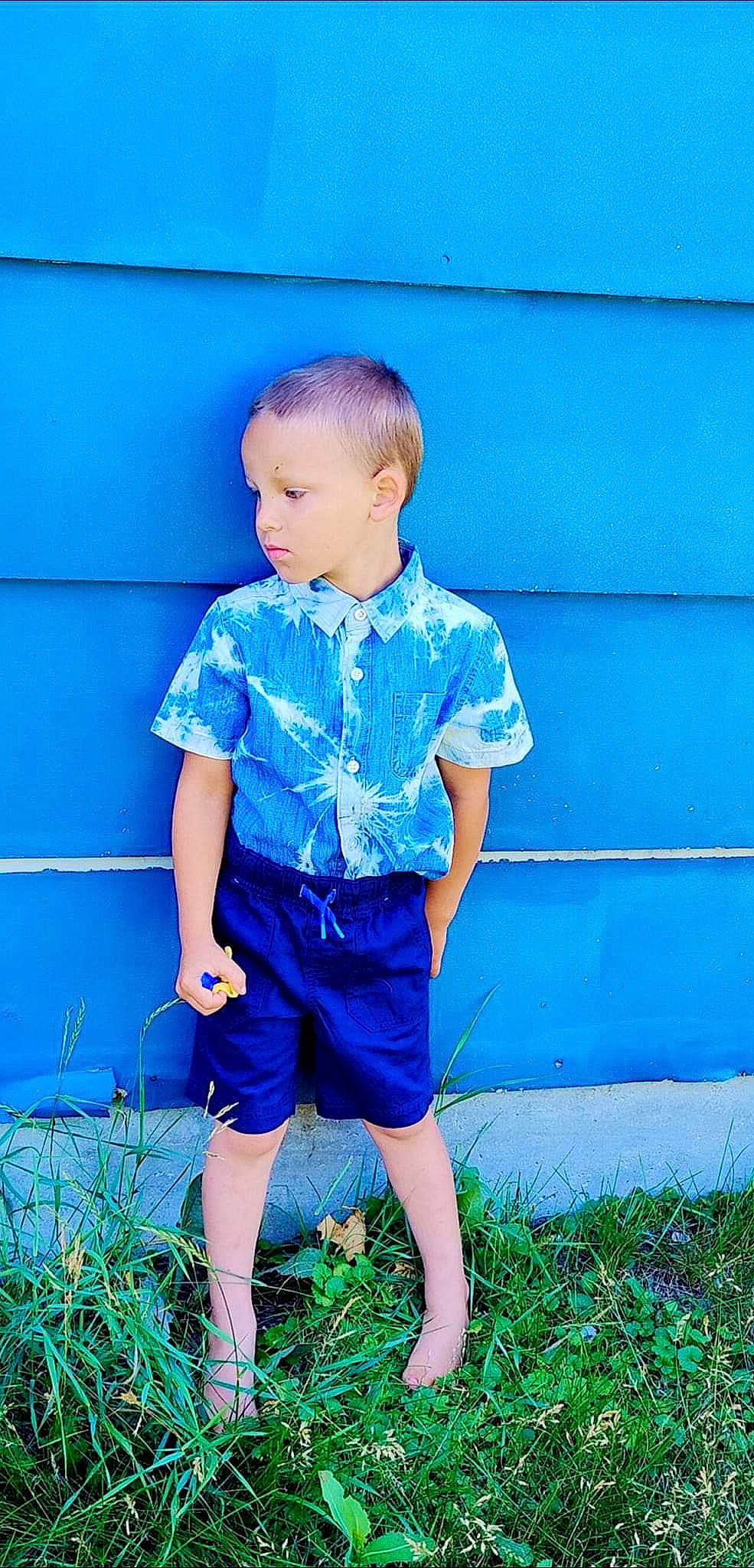 Joziah is registered to the contest to win money with this photo: azure, baby_toddler_clothing, blue, child, denim, electric_blue, fun, grass, happy, human_leg, magenta, pattern, people_in_nature, person, plant, shorts, sitting, sleeve, standing, t_shirt