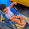 toddler, child, stroller, blue, yellow, vehicle, sidewalk, outdoor, sunlight, sleeping, baby, person, casual_clothing, footwear, wheel, urban, daytime, relaxing, infant, transport