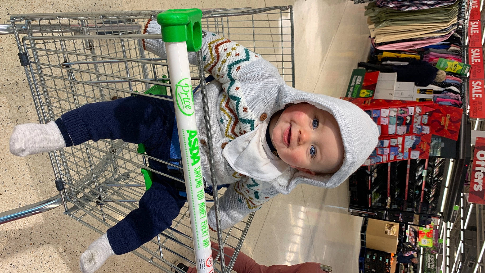 Fletcher is registered to the contest to win money with this photo: baby, baby_products, child, city, fun, hat, headwear, hoodie, joy, person, recreation, shelf, smile, toddler, winter