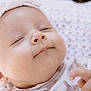 animal_print, baby, baby_clothing, blanket, child, close_up, cute, face, headband, indoors, infant, newborn, onesie, peaceful, portrait, resting, sleeping, smile, soft_lighting, soft_texture