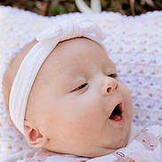 Alice participe au concours pour gagner de l'argent avec cette photo : apparel, baby, blanket, bow, child, close_up, cozy, cute, face, headband, infant, natural_light, outdoor, patterned_clothing, portrait, relaxed, sleepy_face, soft_texture, yawning, young_child