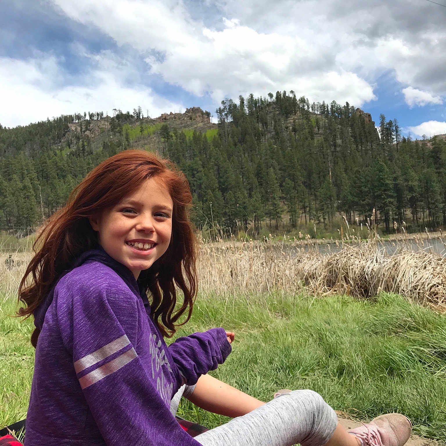 Adrienne is registered to the contest to win money with this photo: beauty, botany, grass, grassland, green, happy, joy, leisure, meadow, mountain, natural_environment, people_in_nature, person, photography, sitting, sky, smile, spring, summer, tree