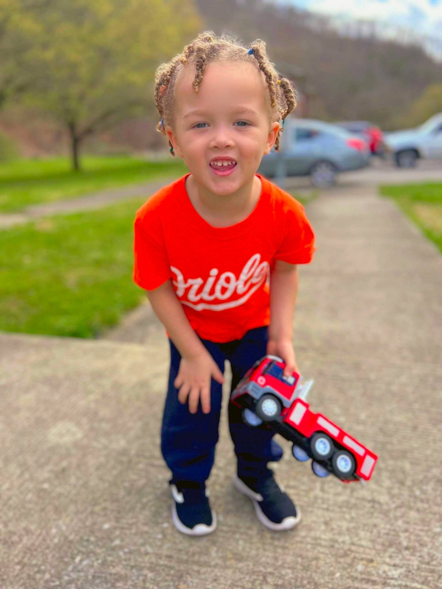 Isaiah is registered to the contest to win money with this photo: asphalt, baby_toddler_clothing, car, child, electric_blue, face, facial_expression, fun, grass, happy, leisure, person, recreation, shoe, sleeve, smile, sneakers, summer, t_shirt, toddler