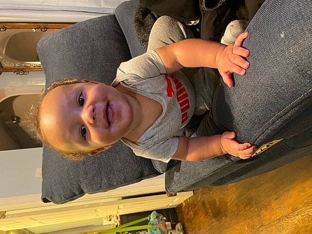 Ronnell is registered to the contest to win money with this photo: baby, baby_toddler_clothing, child, comfort, elbow, flooring, fun, gesture, hat, human_leg, joy, mouth, person, sitting, smile, t_shirt, thigh, thumb, toddler, tree