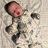 newborn, baby, sleeping, infant, portrait, onesie, pajamas, mittens, bed, bedding, blanket, indoors, lying_down, closed_eyes, peaceful, cute, cartoon_pattern, soft_lighting, nursery, photography