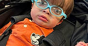 Harvee joined the competition — help win amazing prizes! baby, child, infant, stroller, eyeglasses, blue_glasses, orange_shirt, mickey_mouse, harness, seated, portrait, indoor, public_building, background, face, brown_hair, looking_at_camera, baby_carriage, safety_strap, photography