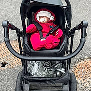 Ouazna participe au concours pour gagner de l'argent avec cette photo : baby, stroller, pacifier, red_snowsuit, hat, sleeping, infant, outdoor, asphalt, wheels, black_stroller, child, winter_clothing, bundle, peaceful, cute, urban, transport, seat, baby_gear