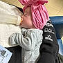 Aurora is registered to the contest to win money with this photo: baby, bottle, pink_bow, headwrap, onesie, polka_dot, infant, feeding, towel, adult_arm, sweatshirt, text_on_clothing, floor_tile, indoor, closeup, side_profile, human, holding, resting, cute