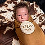 Akari joined the competition — help win amazing prizes! baby, infant, swaddled, brown_cloth, wooden_plaque, one_month, cow_print, cushion, face, portrait, newborn, resting, child, young, indoors, soft_texture, cute, head, expression, closeup